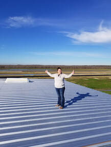 Metal Roof with Alisha Carpenter Standing on top giving two thumbs up
